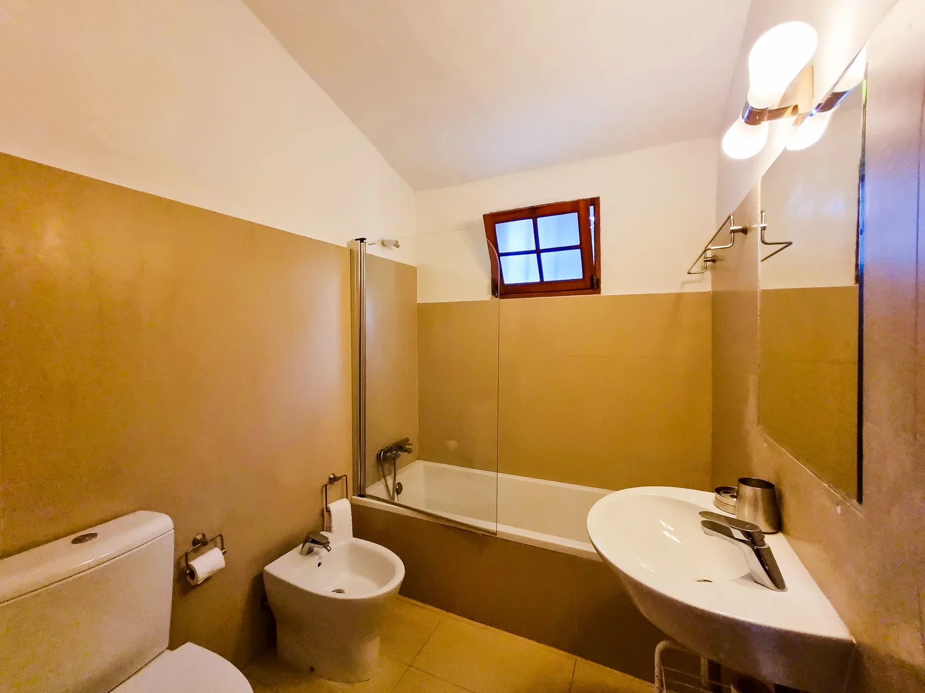Un baño con bañera, lavabo y una ventana pequeña.