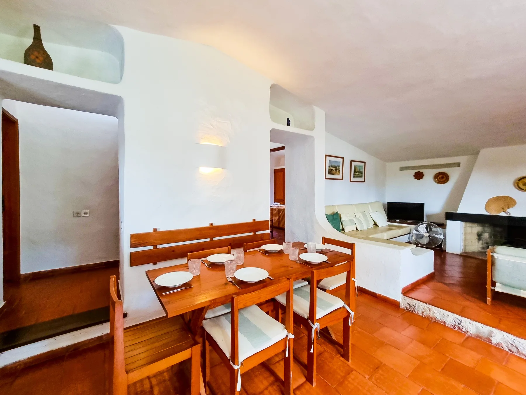 Comedor con mesa de madera y asientos junto a una zona de estar.