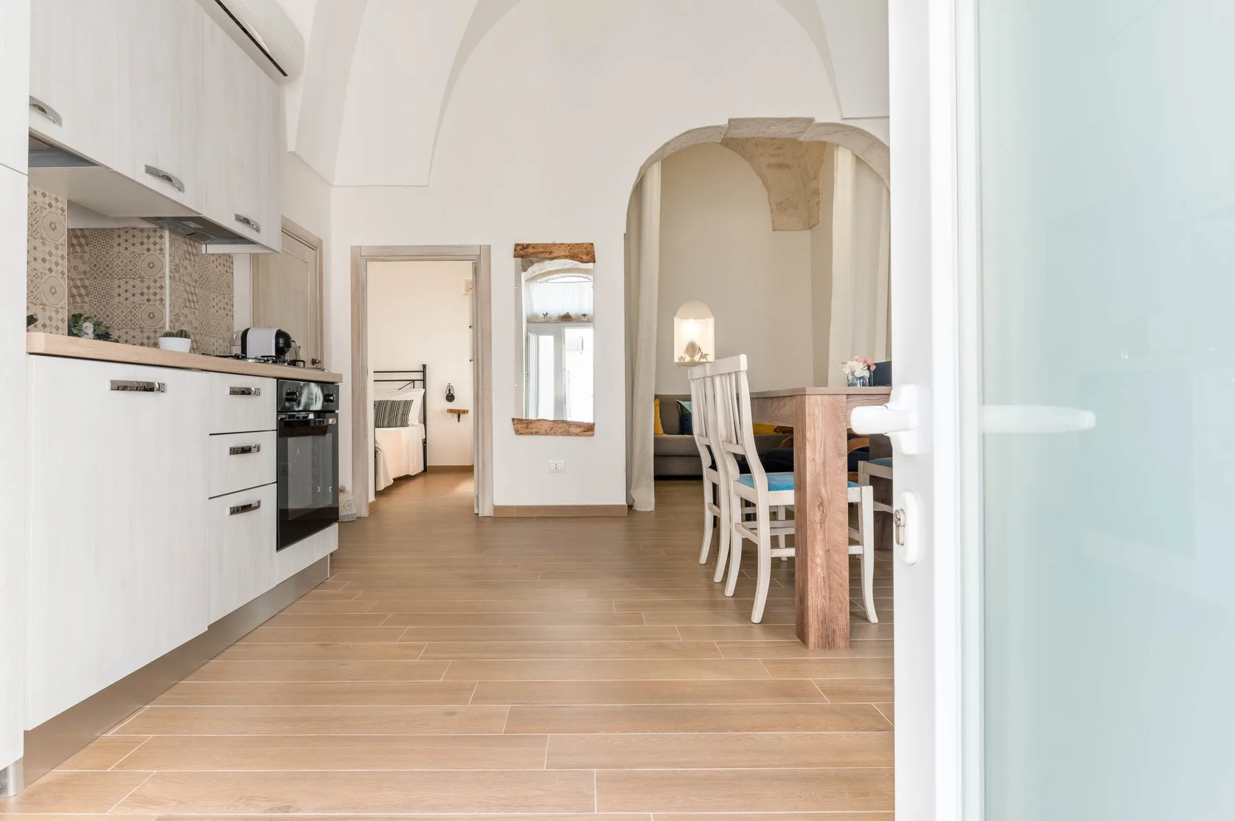 A bright kitchen and dining area with white cabinetry and a wooden table.