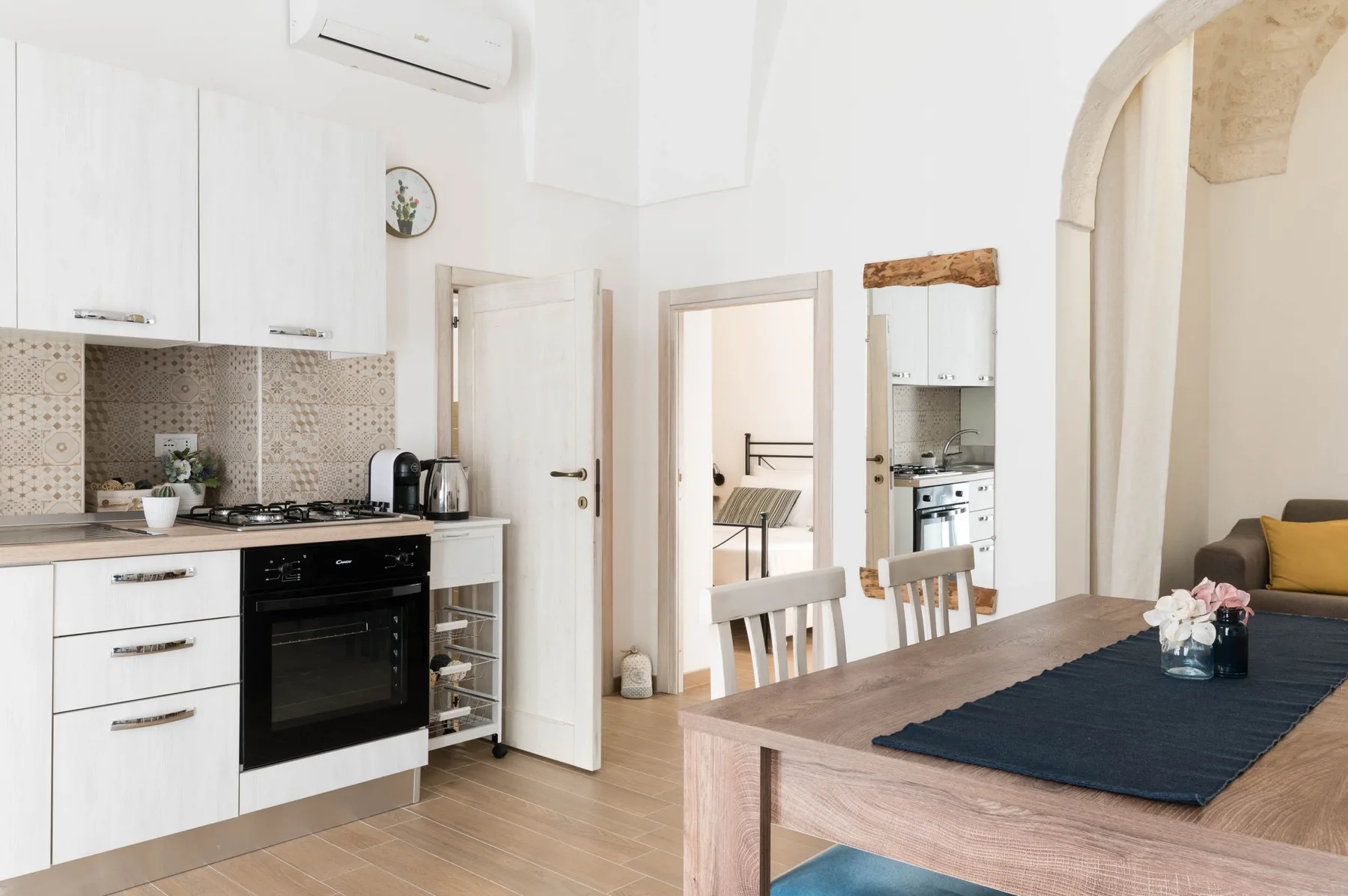 A bright kitchen and dining area with white cabinetry and a wooden table.