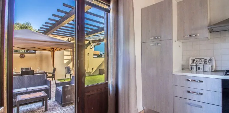 A kitchen beside glass doors opening onto an outdoor patio with seating.