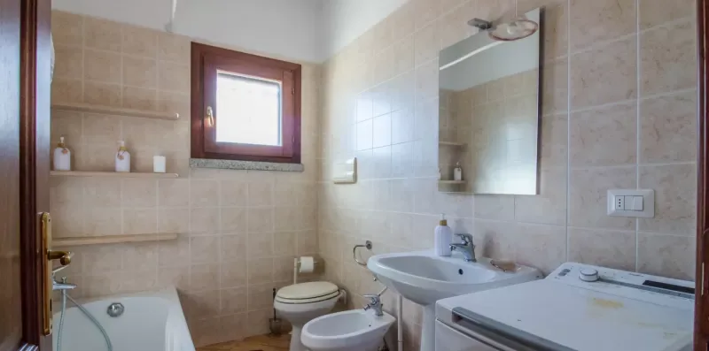 A tiled bathroom with a bathtub, toilet, sink, and wall mirror.