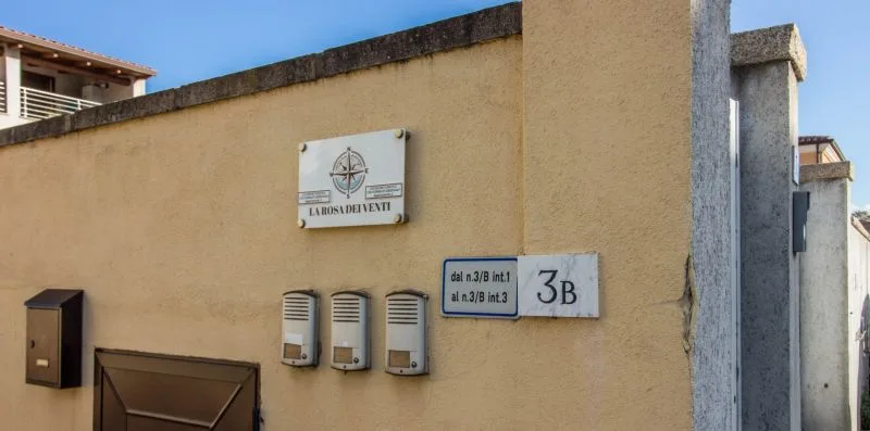 Exterior view of a beige building wall with mounted signs and utility boxes.