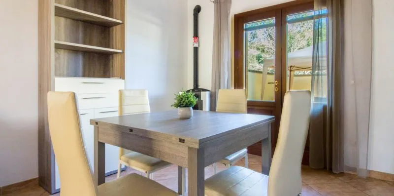 A dining area with a wooden table and seating beside glass doors.