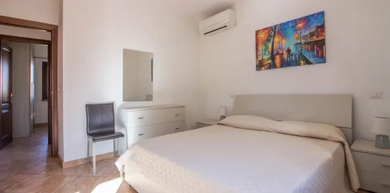 A bedroom with a neatly made bed and colorful wall art.
