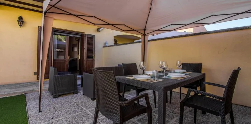 An outdoor dining area with a table and seating beneath a canopy.