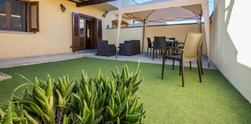 A small outdoor patio with seating beneath a shade canopy.
