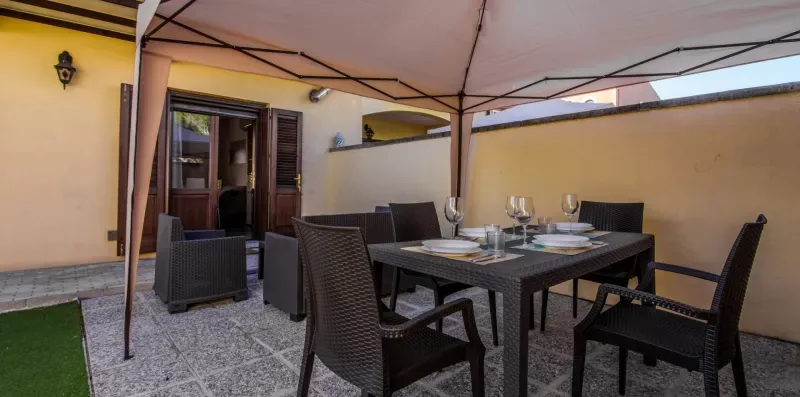 An outdoor dining area under a canopy, with a table and seating.