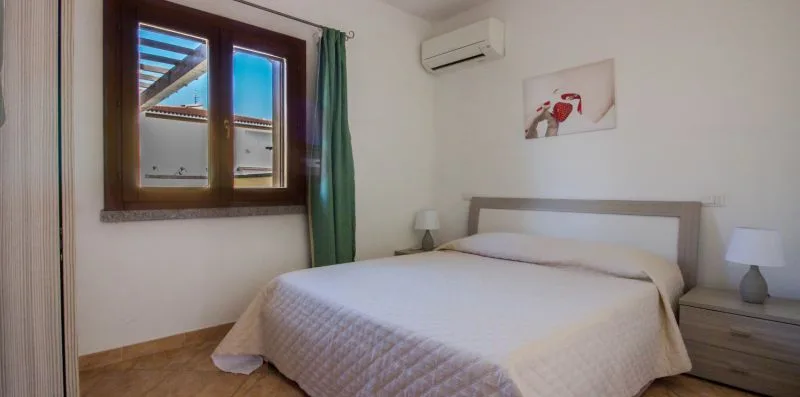 A bedroom with a double bed, green curtains, and a window.