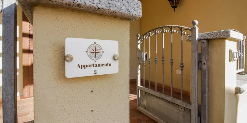An apartment entrance with a decorative metal gate and a wall-mounted sign.
