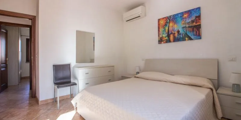 A bedroom with a bed, dresser, and colorful wall art.