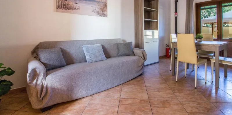 A living and dining area with gray seating and a table beside a glass door.