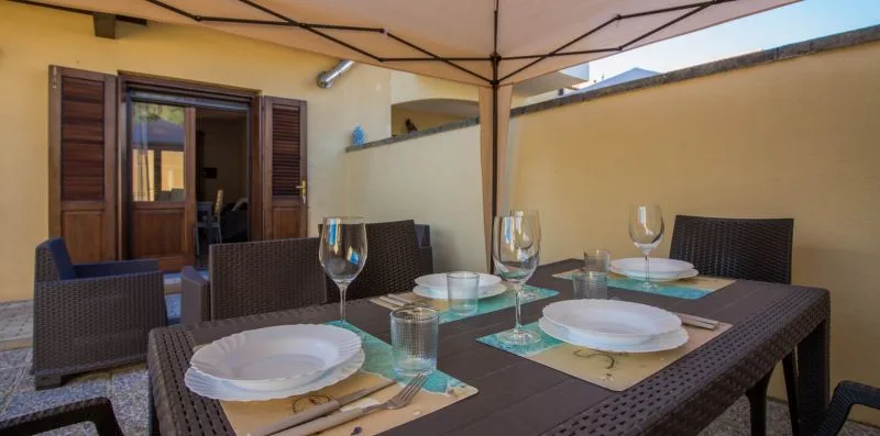 An outdoor dining table is set beneath a large patio umbrella.