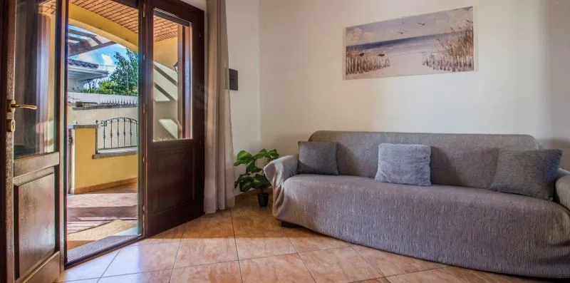 A living room with gray seating and a glass door opening to a terrace.