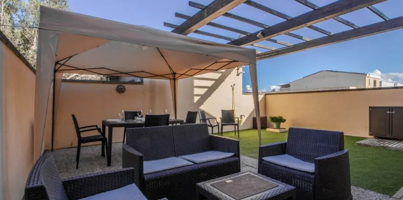 An outdoor patio seating area sits beneath a canopy beside a small lawn.