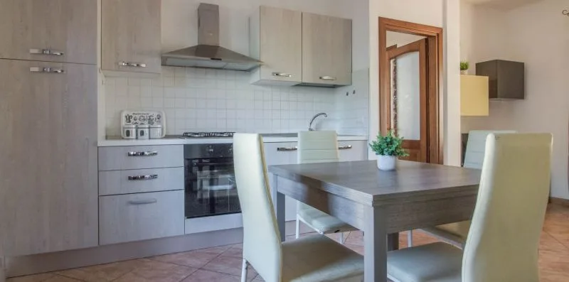 A kitchen and dining area with a table and pale seating.
