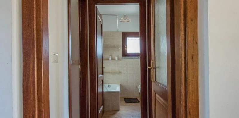 A hallway opens onto a bathroom with a sink and window.