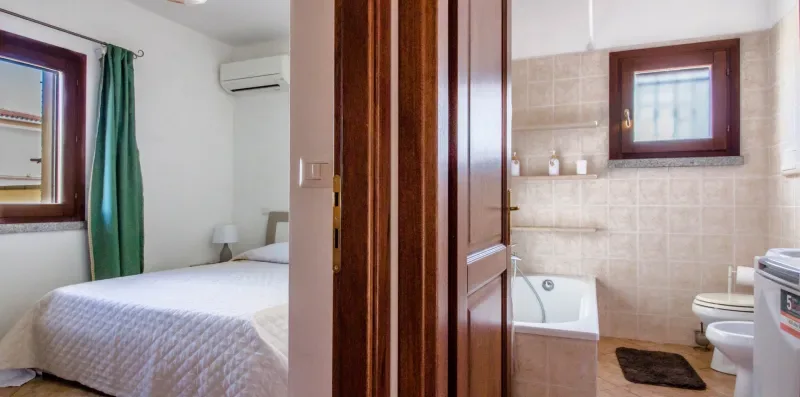 A bedroom and tiled bathroom are visible through an open doorway.