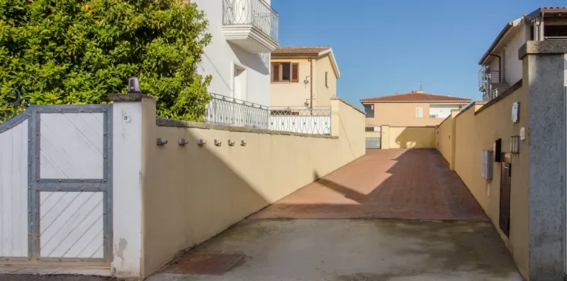 A paved driveway runs between buildings toward a gated entrance.