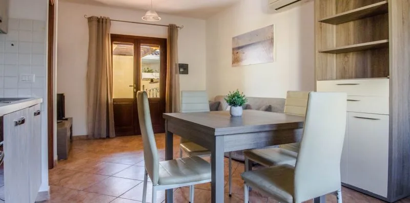 A dining area with a table and chairs beside a curtained glass door.