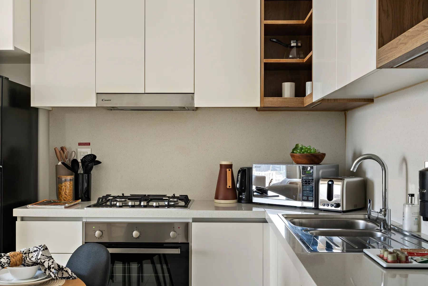 A modern kitchen with white cabinets, a stovetop, and a sink.