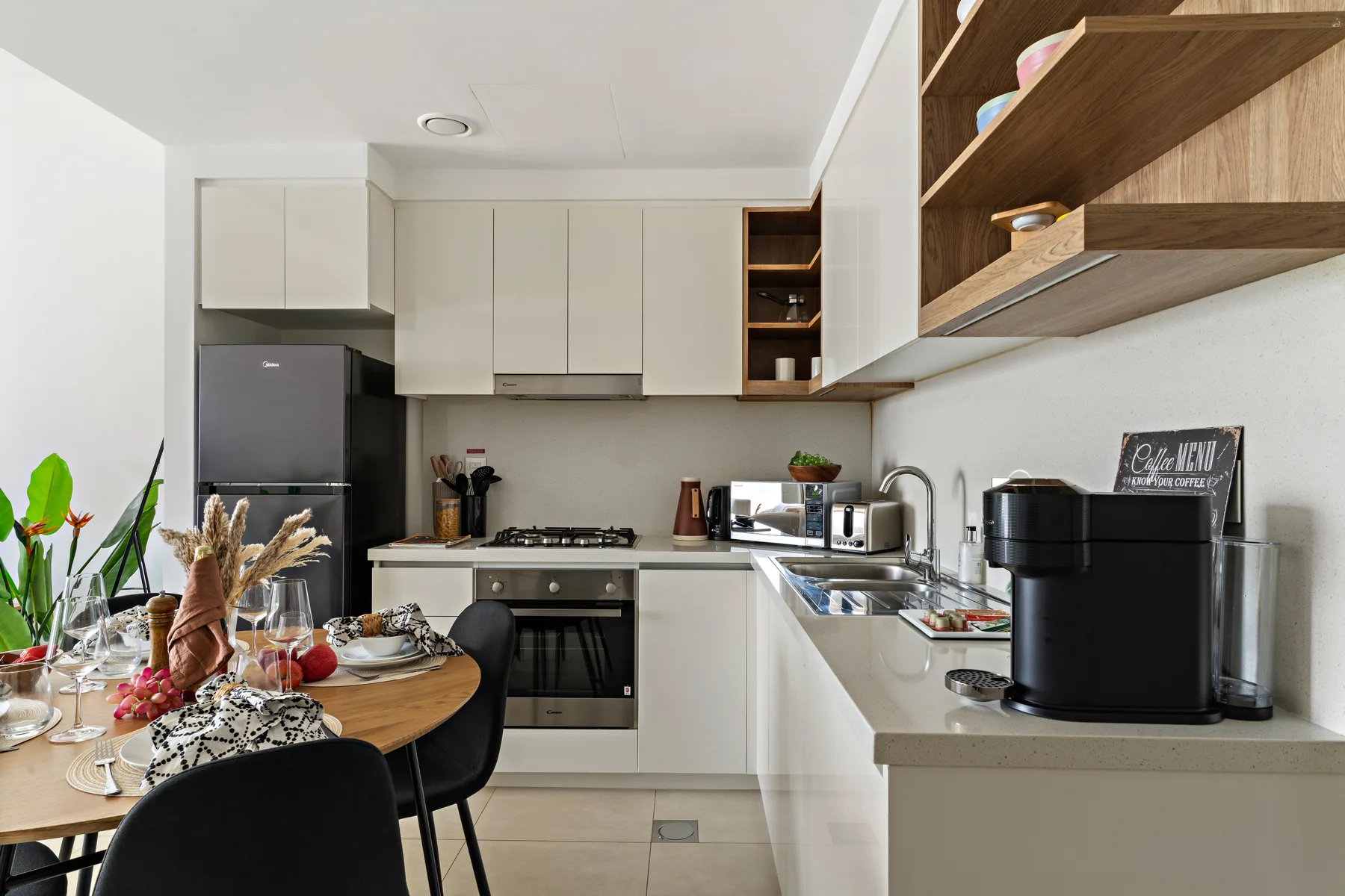 A modern kitchen with white cabinets, a counter, and a dining table.