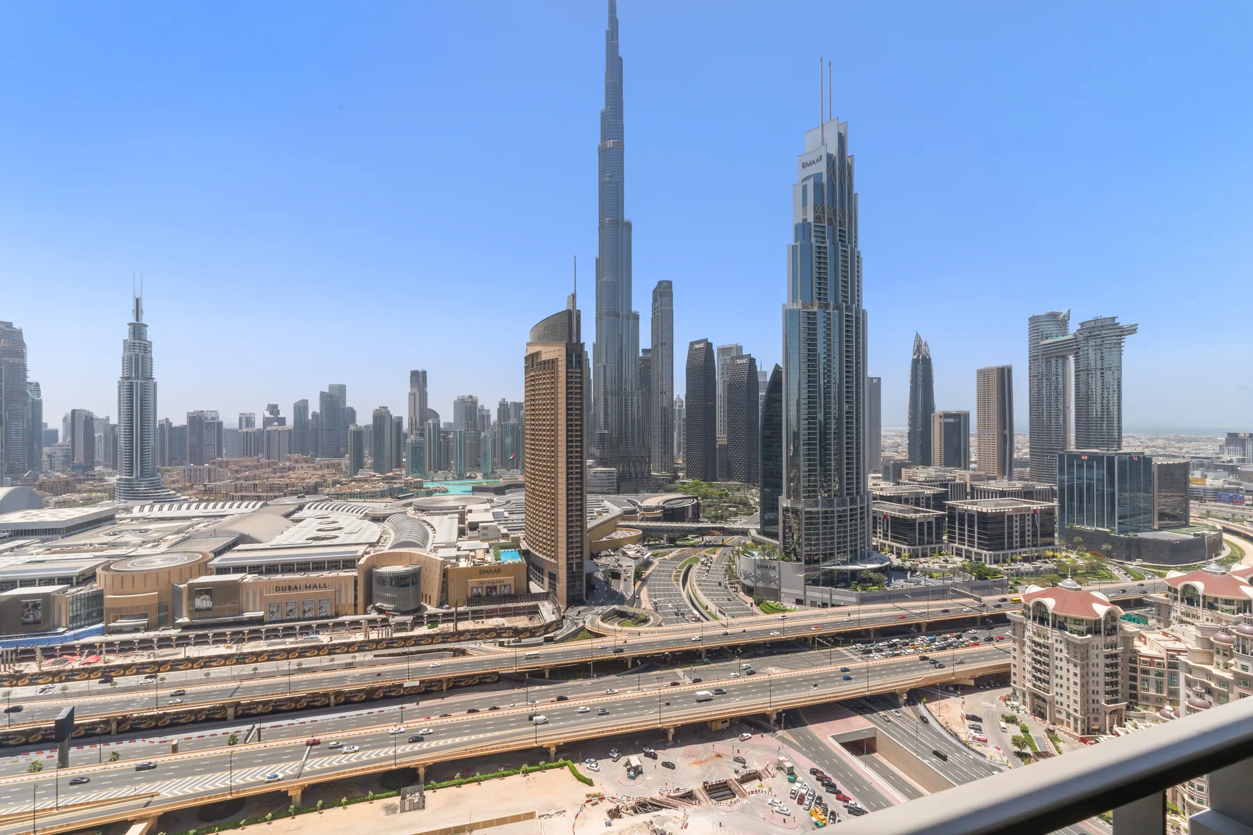 A city skyline with tall skyscrapers rises beyond roads and low-rise buildings.