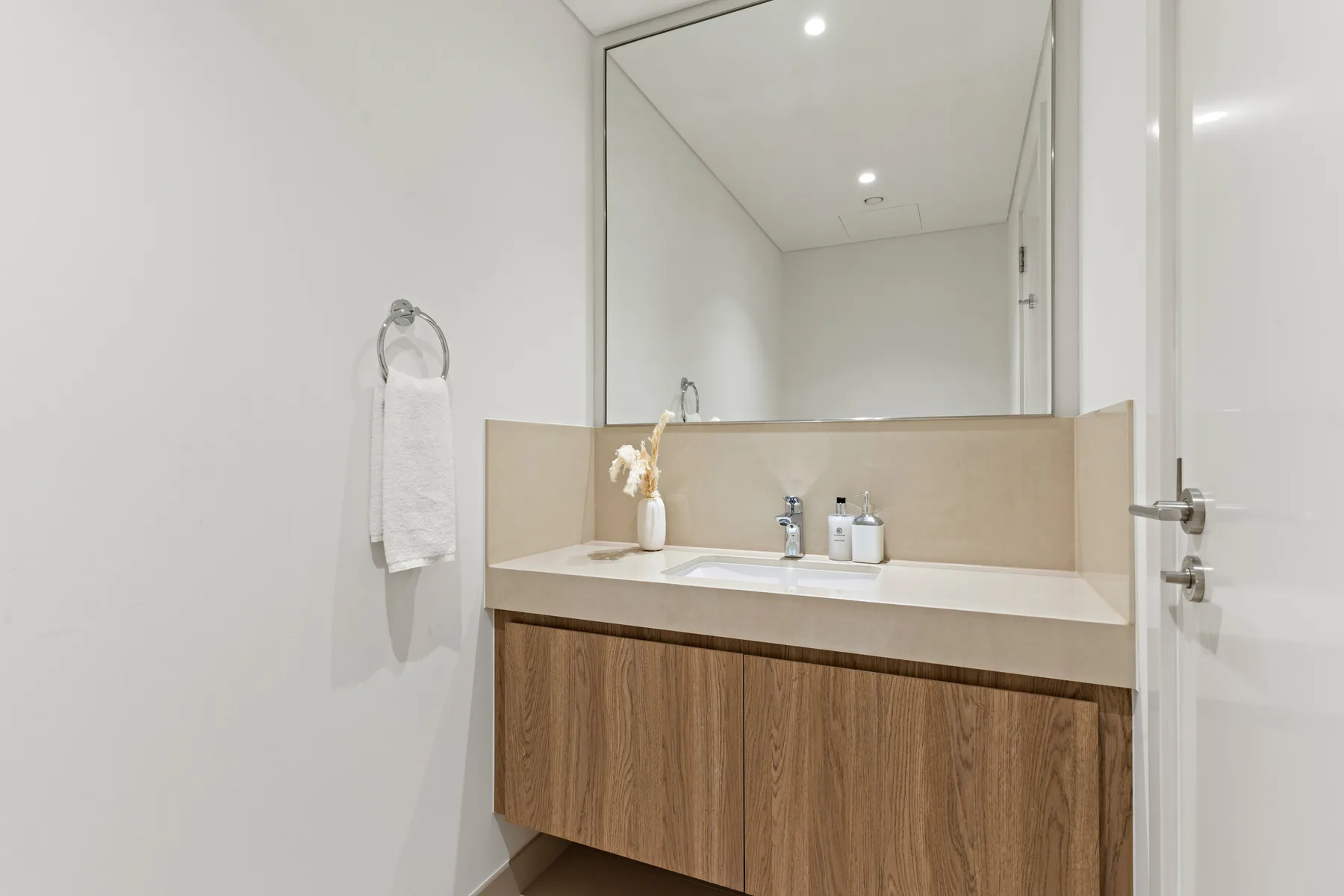 A bathroom vanity with a wide mirror and a towel hanging beside it.