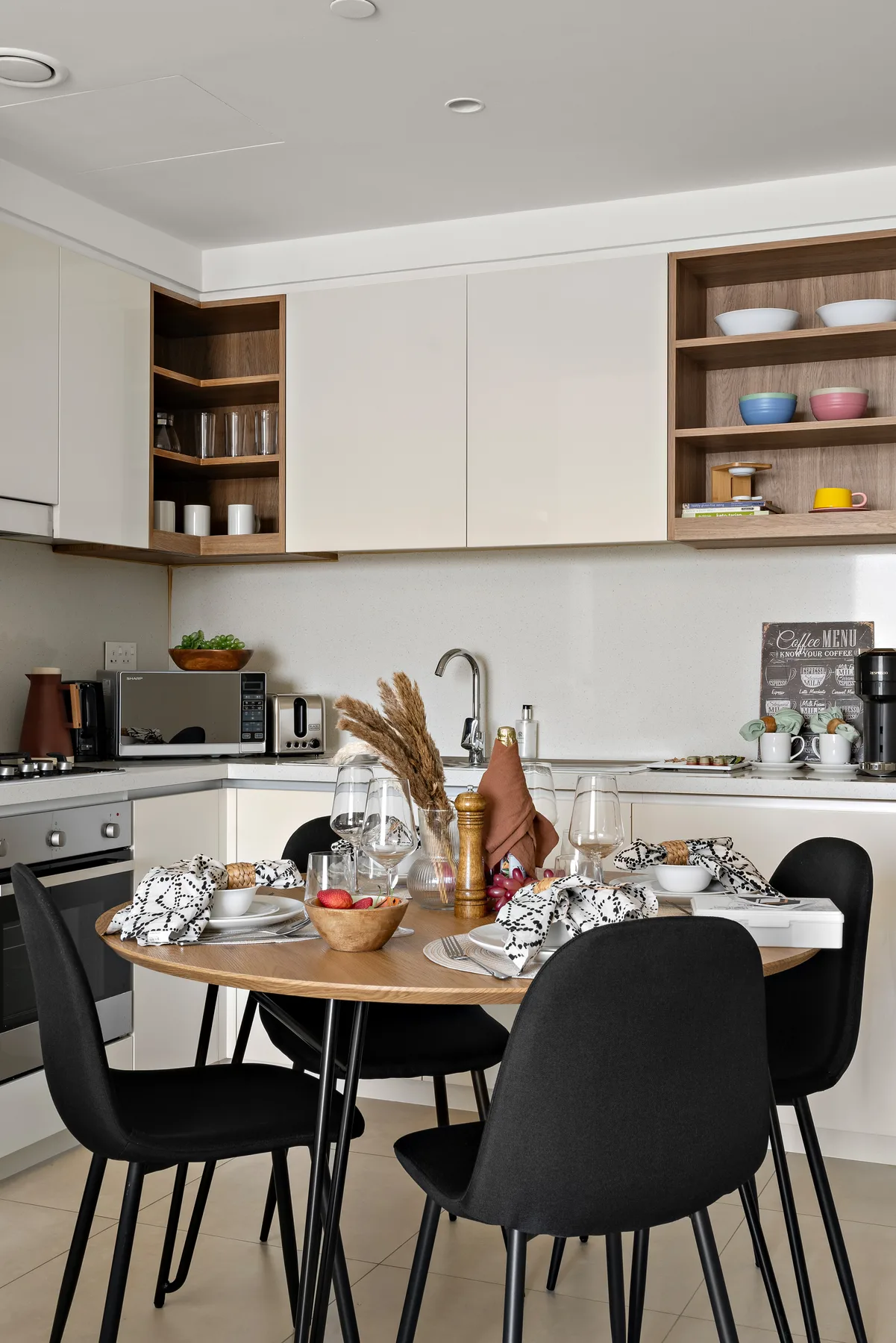 A modern kitchen and dining area with a set table and dark seating.