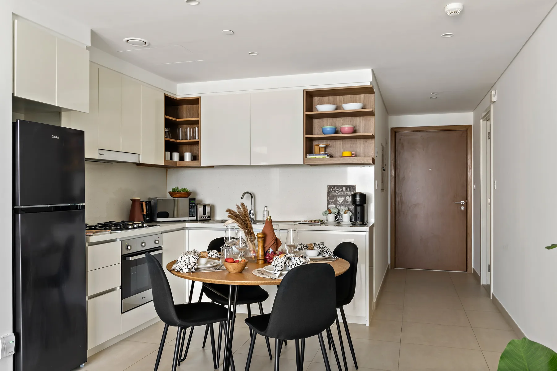 A kitchen and dining area with a round table and black seating.
