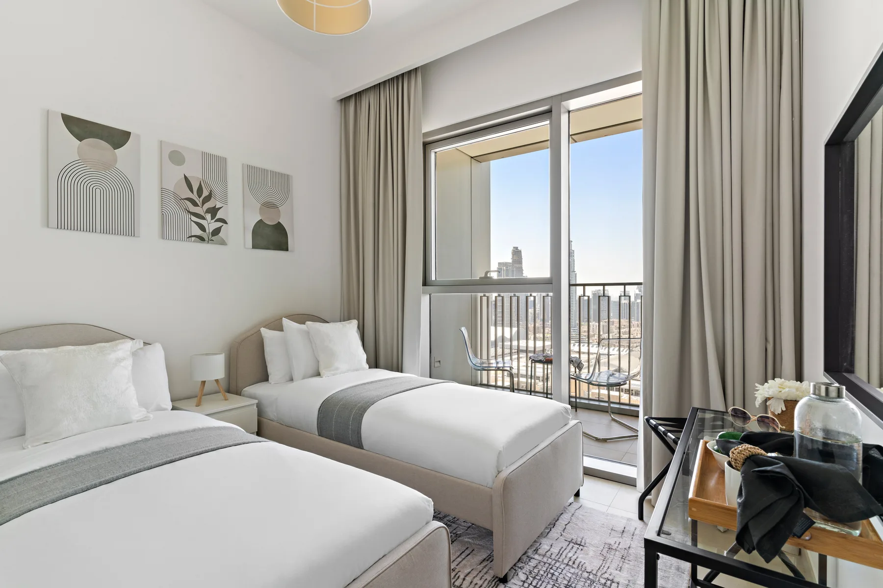 A bright bedroom with two beds and large glass doors opening to a balcony.