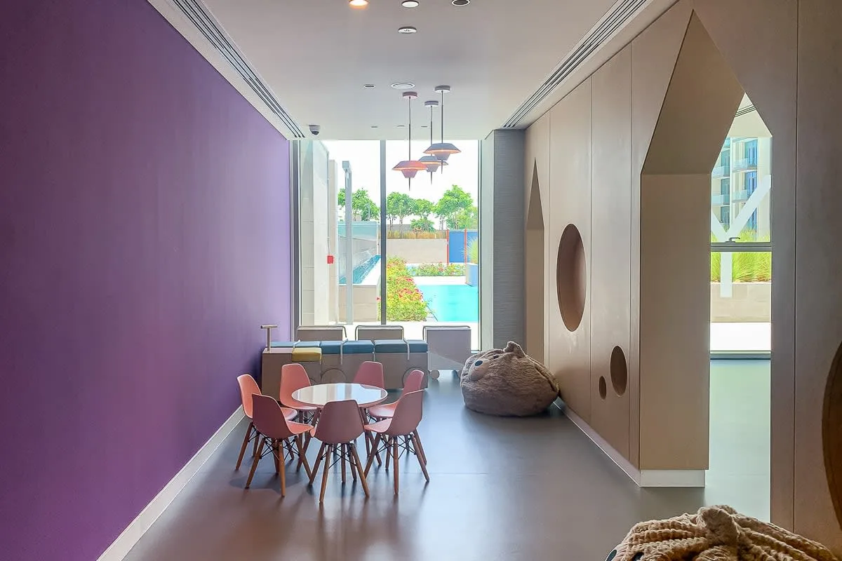 A modern lounge with a dining table and seating beside large windows.