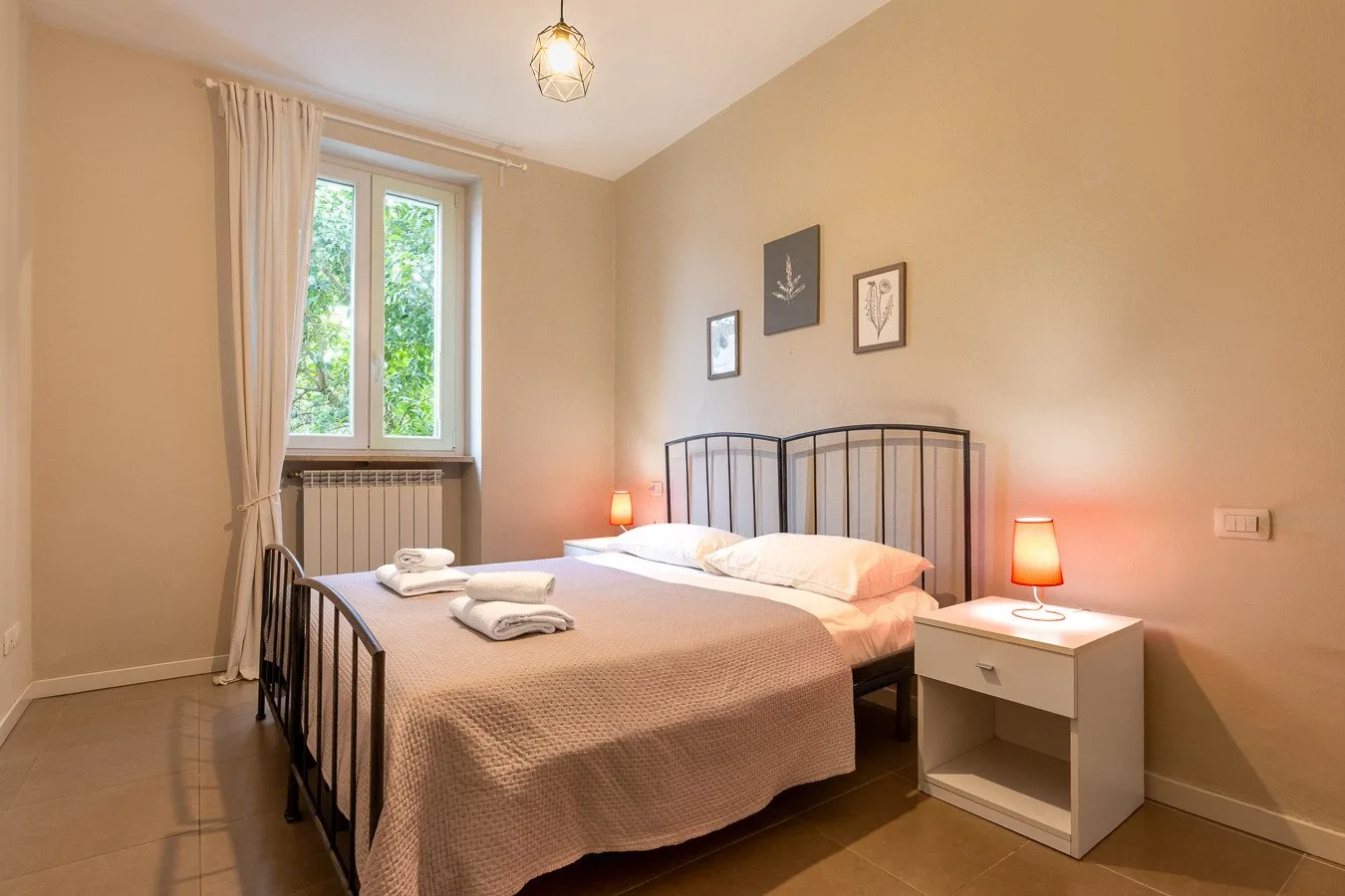 Un dormitorio con una cama doble, mesillas de noche y una ventana alta.