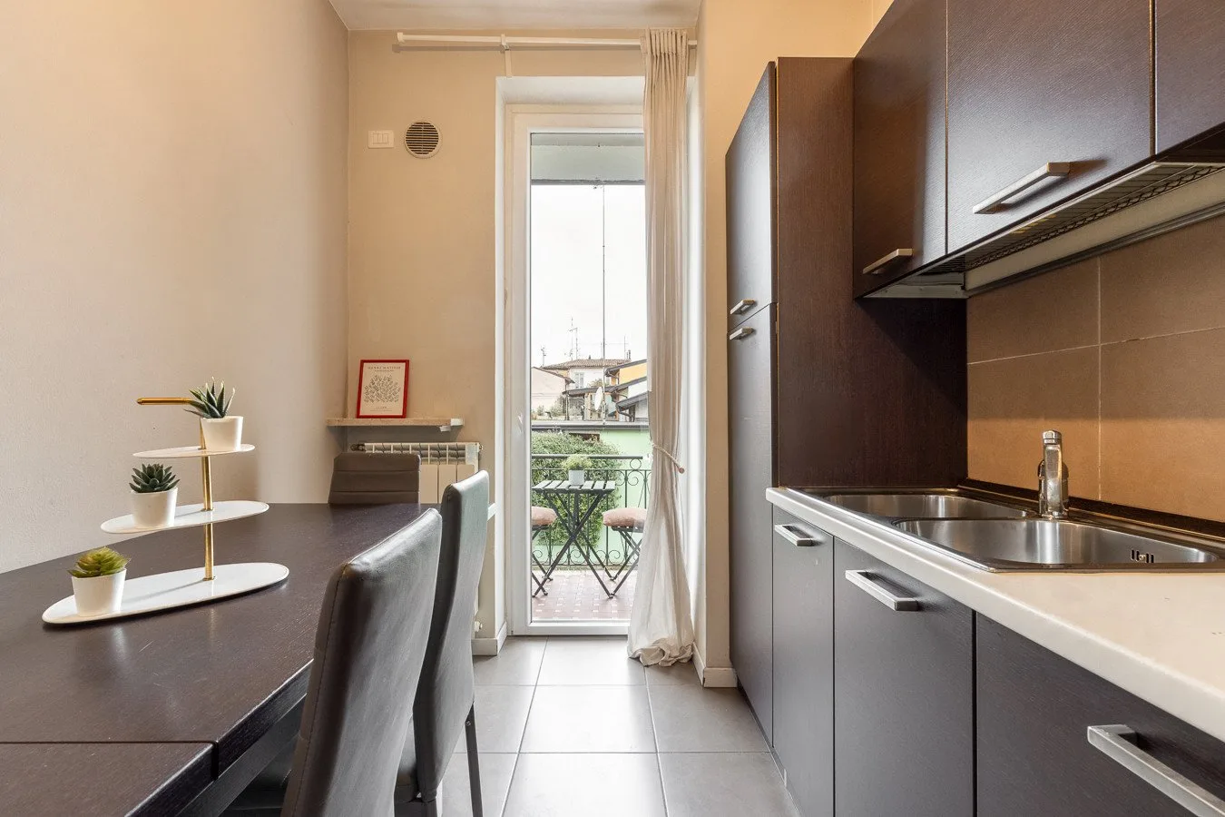 Una cocina estrecha con zona de comedor junto a una puerta de balcón.