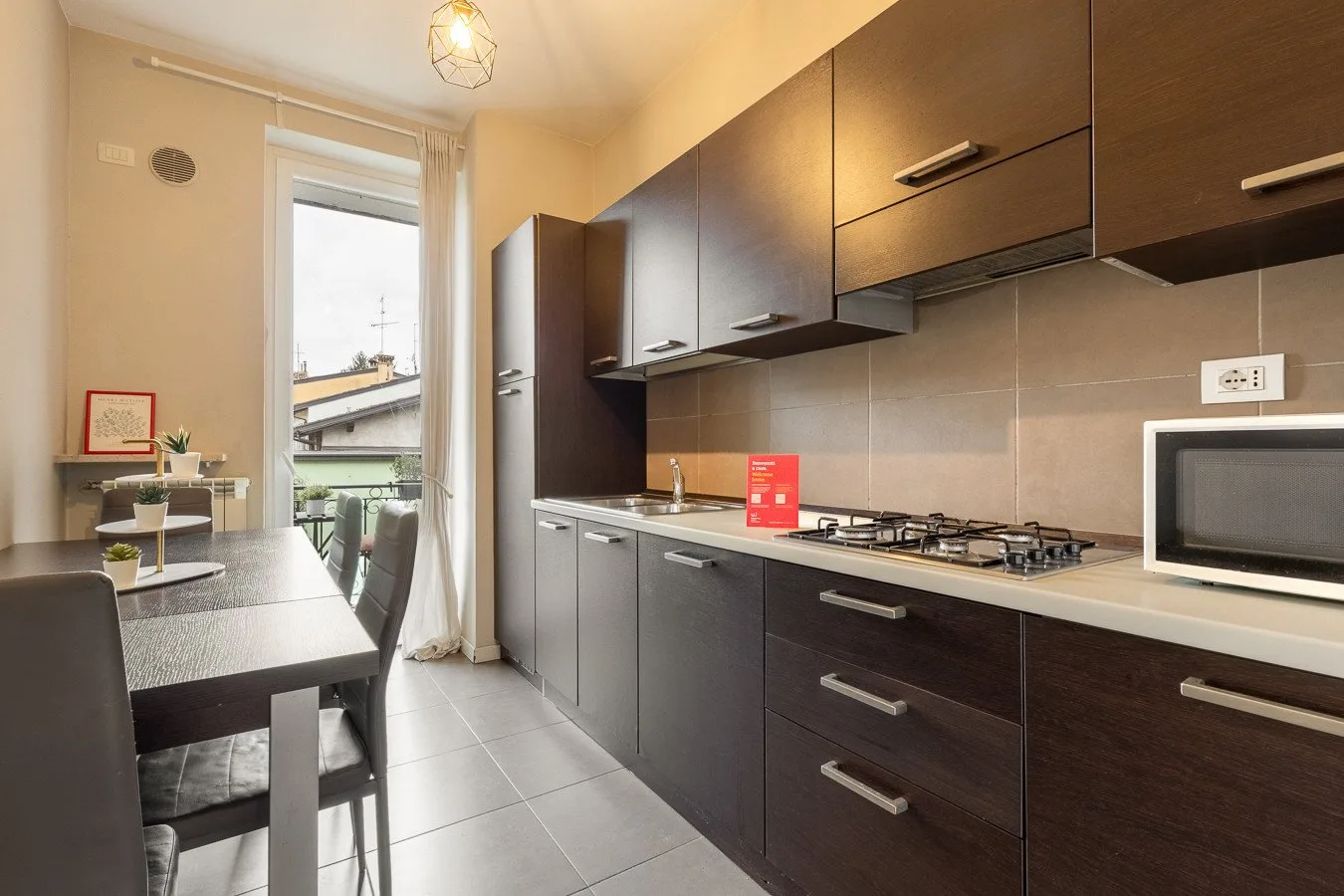 Una cocina compacta con muebles oscuros, una placa de cocina y una pequeña mesa de comedor.