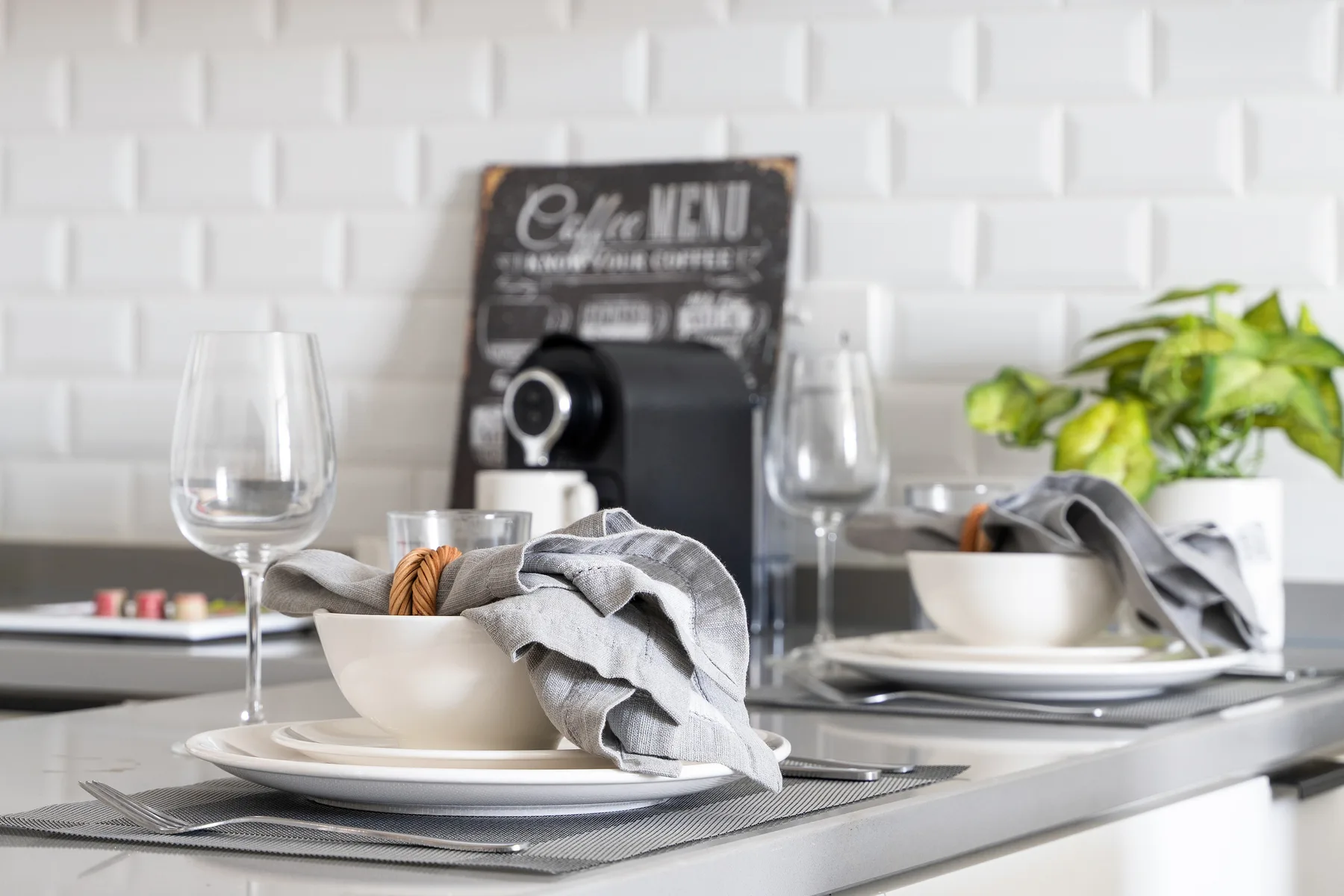 A dining table is set with plates, bowls, glasses, and a small potted plant.