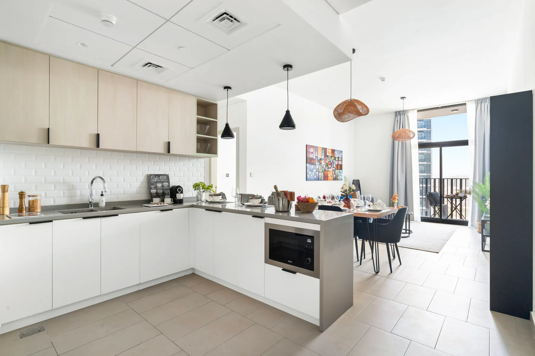 A bright open-plan kitchen and dining area with a counter and pendant lights.
