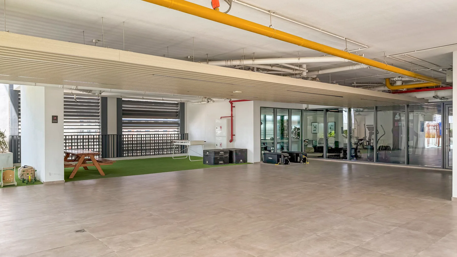 A spacious indoor common area with glass-walled rooms and a small seating area.