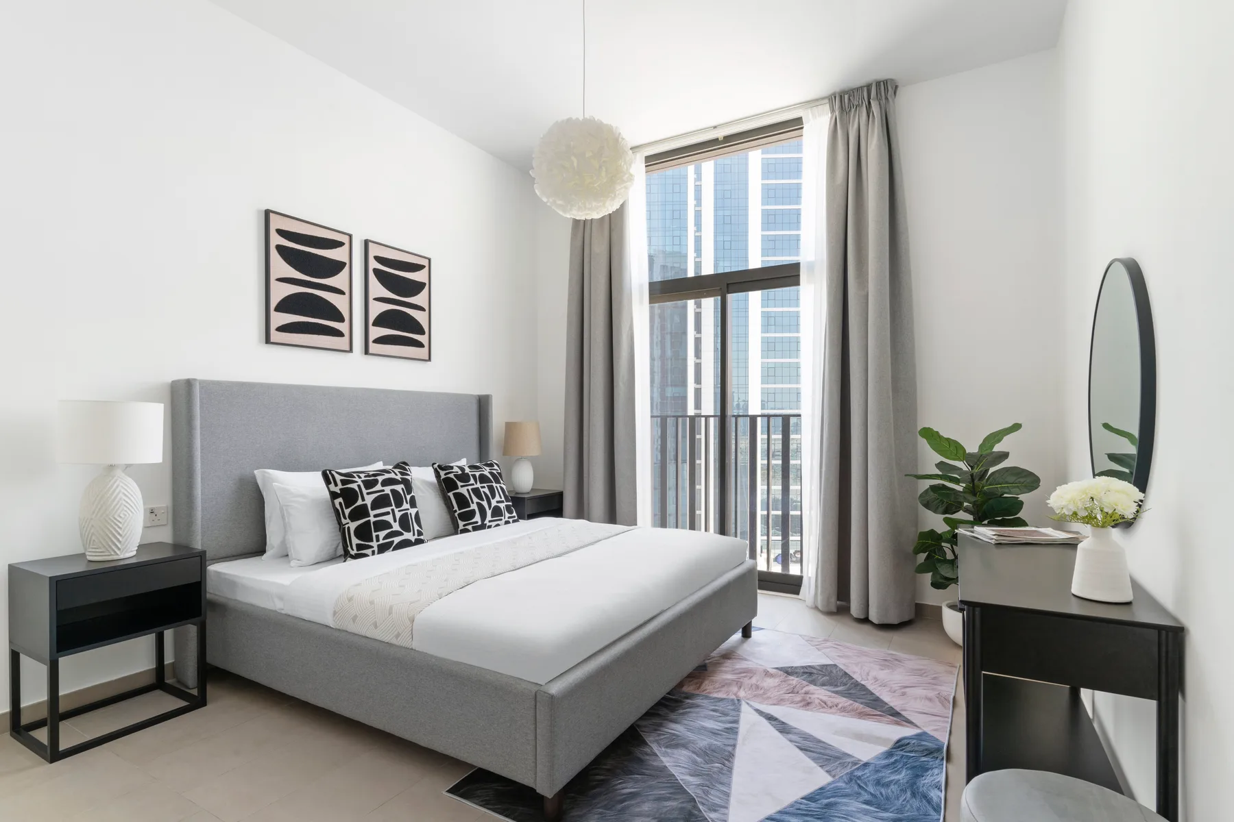 A bright bedroom with a neatly made bed and a large window.