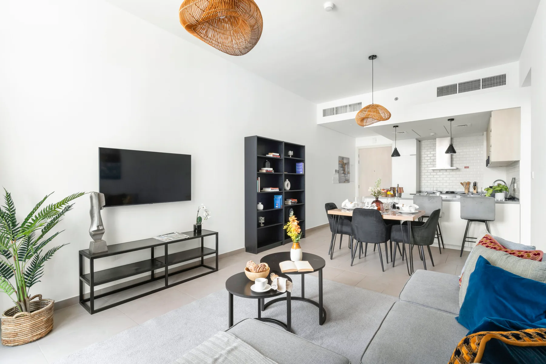 A bright open-plan living room and kitchen with a dining table and seating.