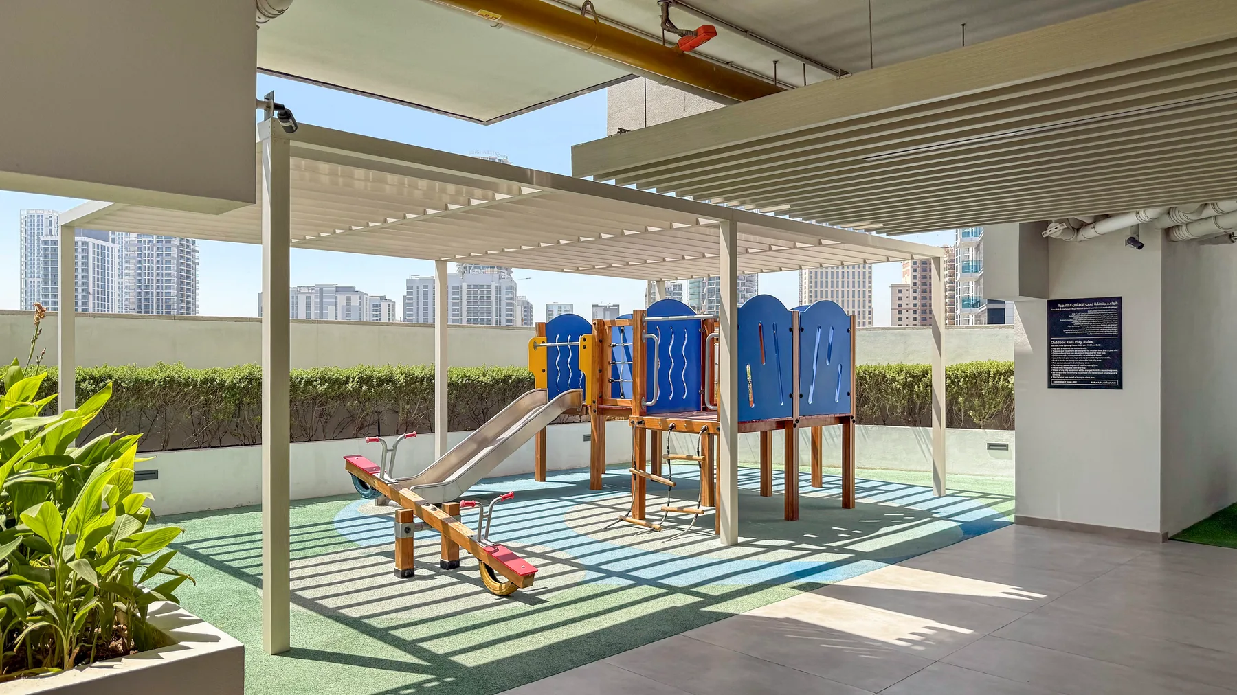 A shaded outdoor playground with slides and climbing equipment.