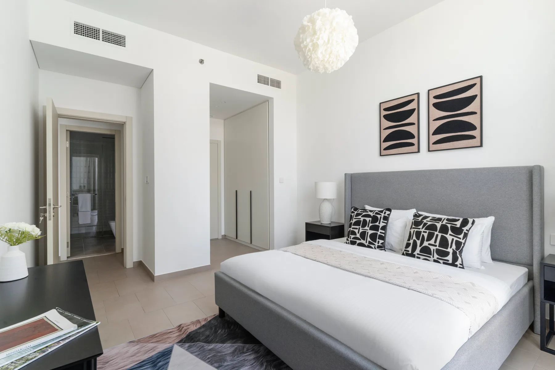A bright bedroom with a large bed and abstract artwork above the headboard.