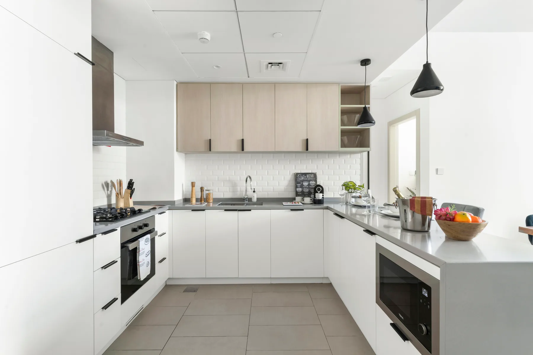 A modern kitchen with white cabinets, a tiled backsplash, and a central island.