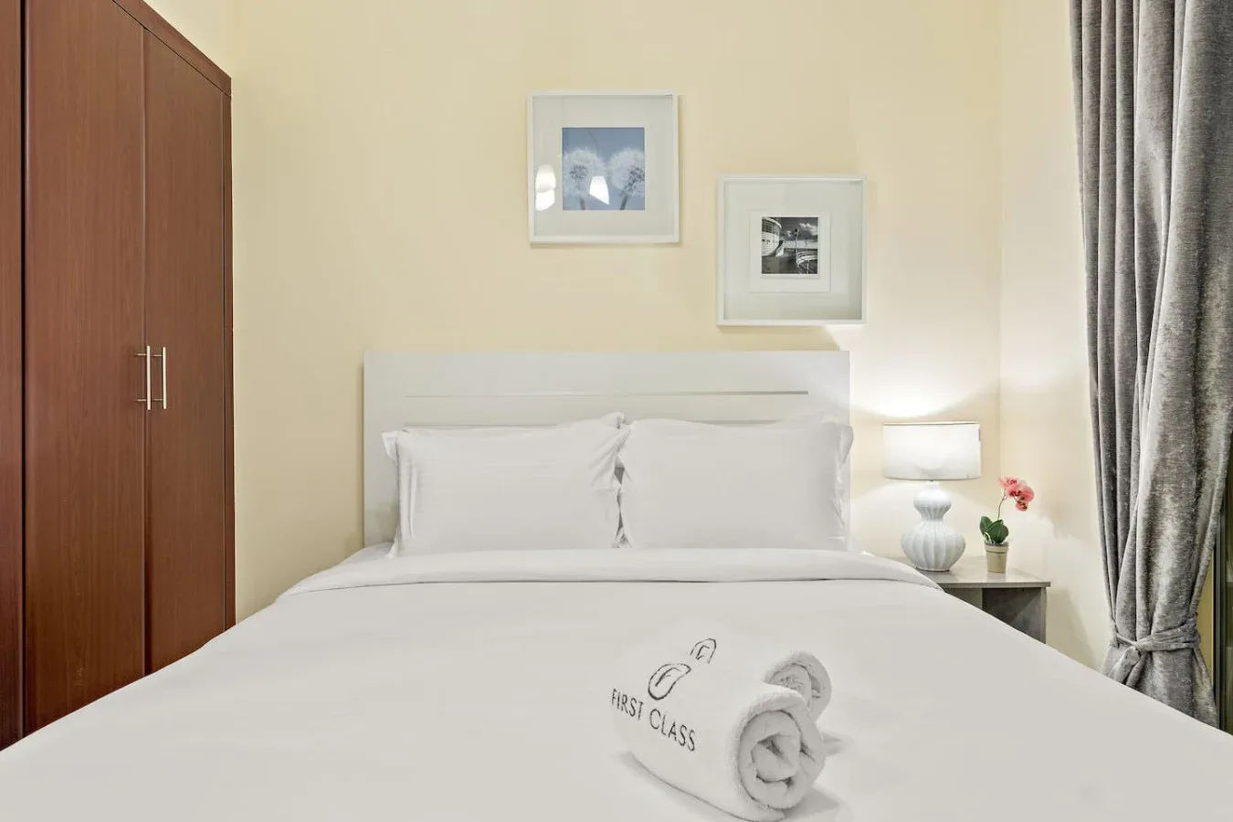 Un dormitorio con una cama bien arreglada y cuadros enmarcados sobre el cabecero.