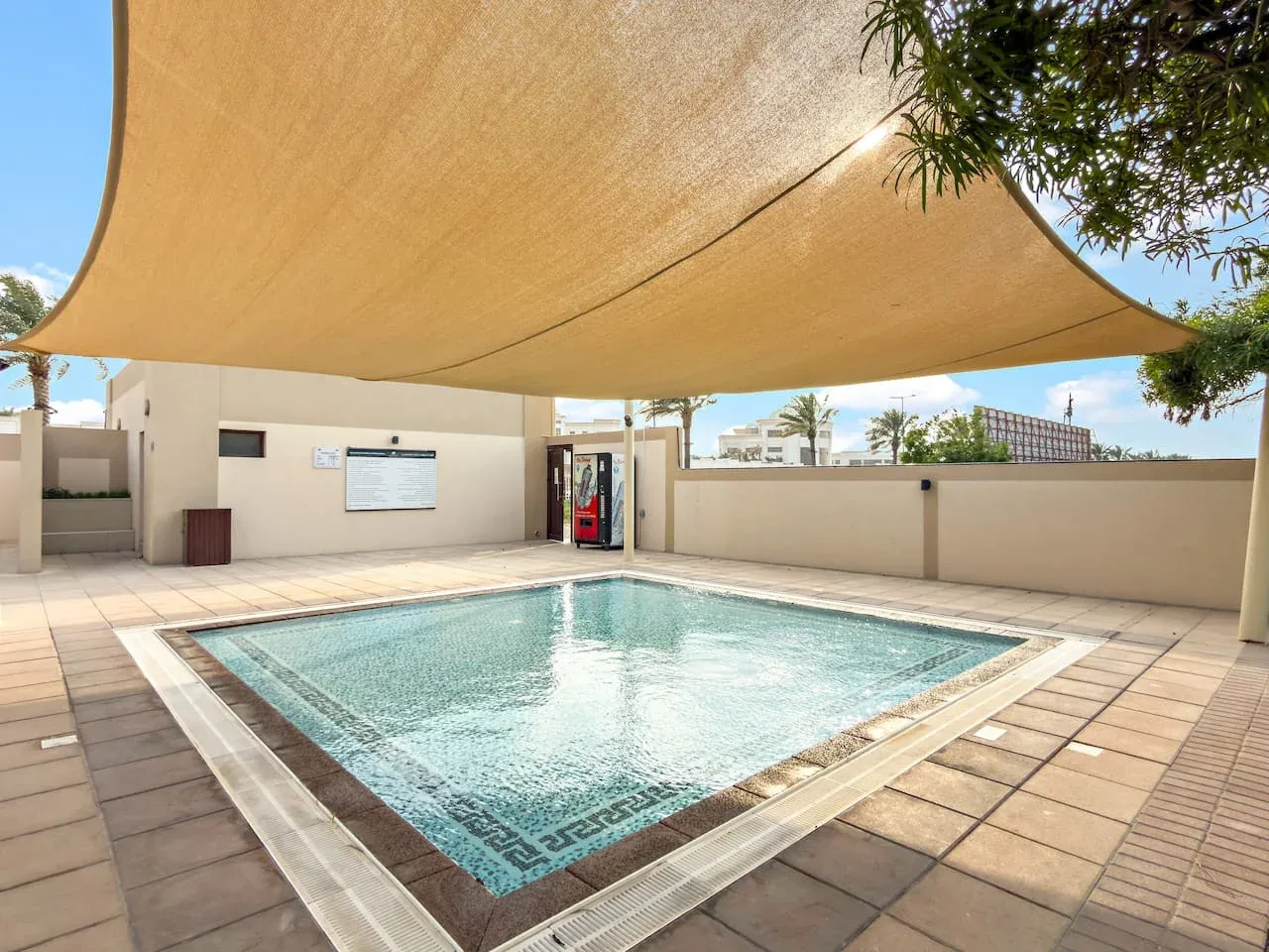 Una piscina al aire libre se encuentra bajo una gran cubierta de sombra.
