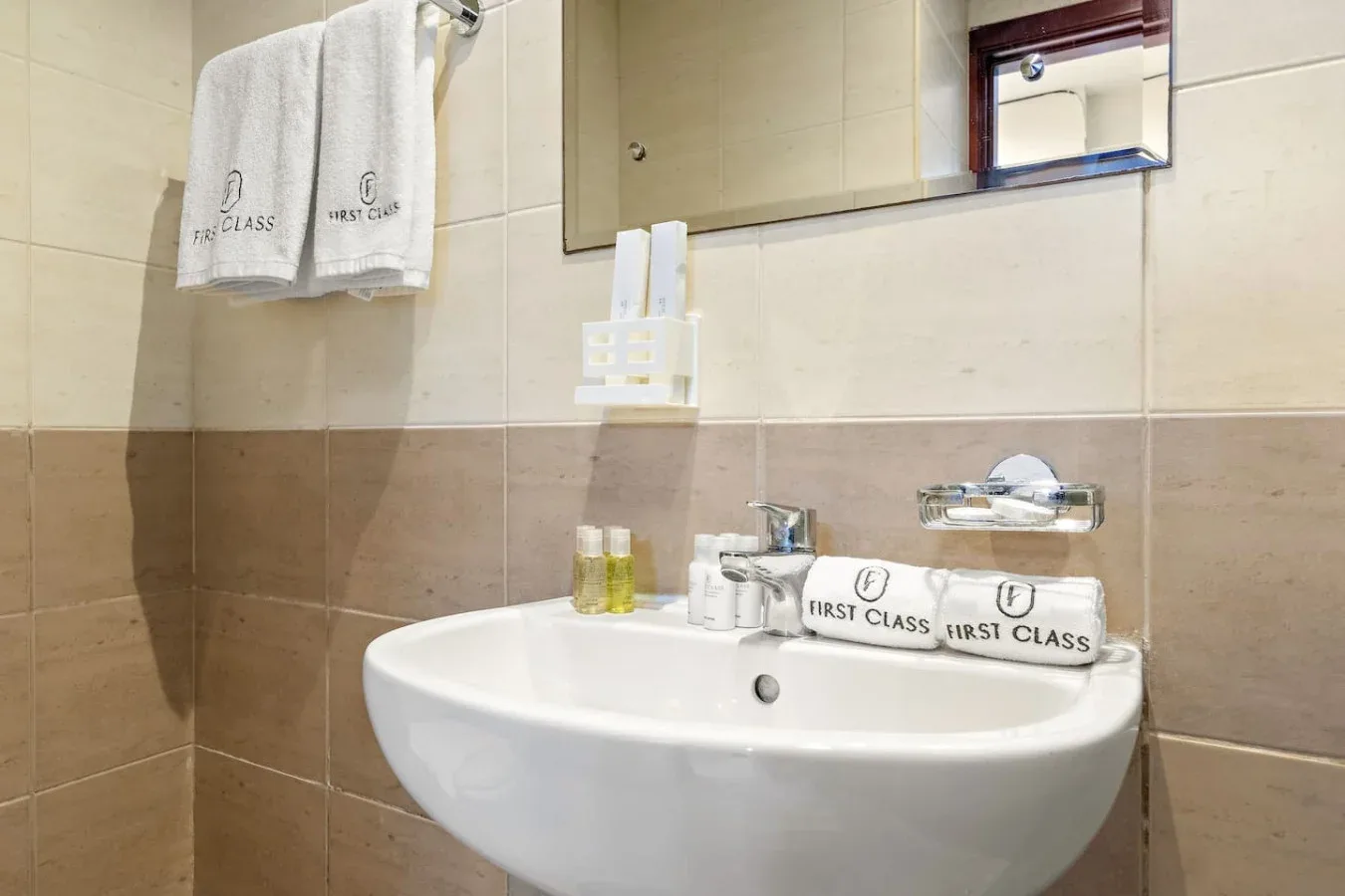 Un lavabo de baño bajo un espejo, con toallas colgadas cerca.