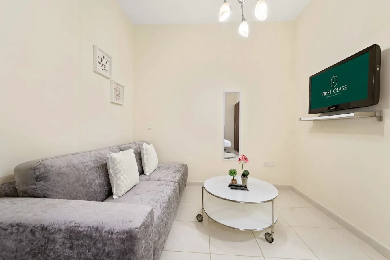 Una sala luminosa con asientos grises y un televisor montado en la pared.