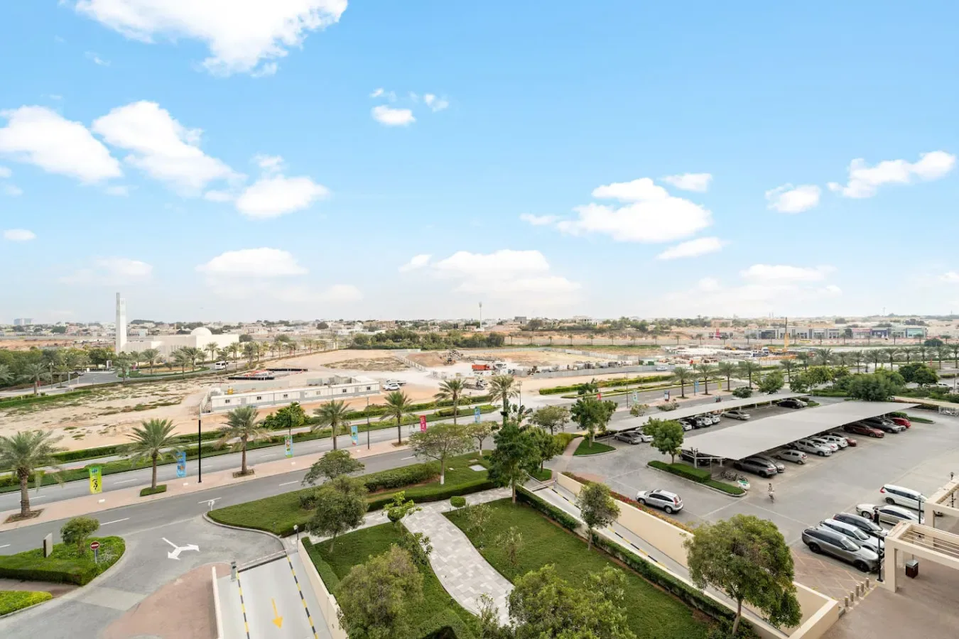 Una zona ajardinada junto a la carretera y el estacionamiento mira hacia un amplio paisaje urbano.