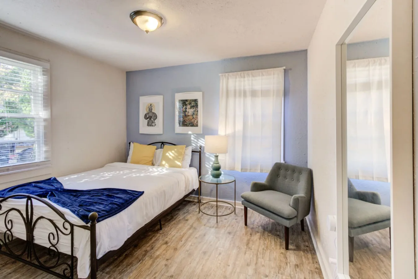 Un dormitorio con una cama, una mesa auxiliar y un sillón tapizado.
