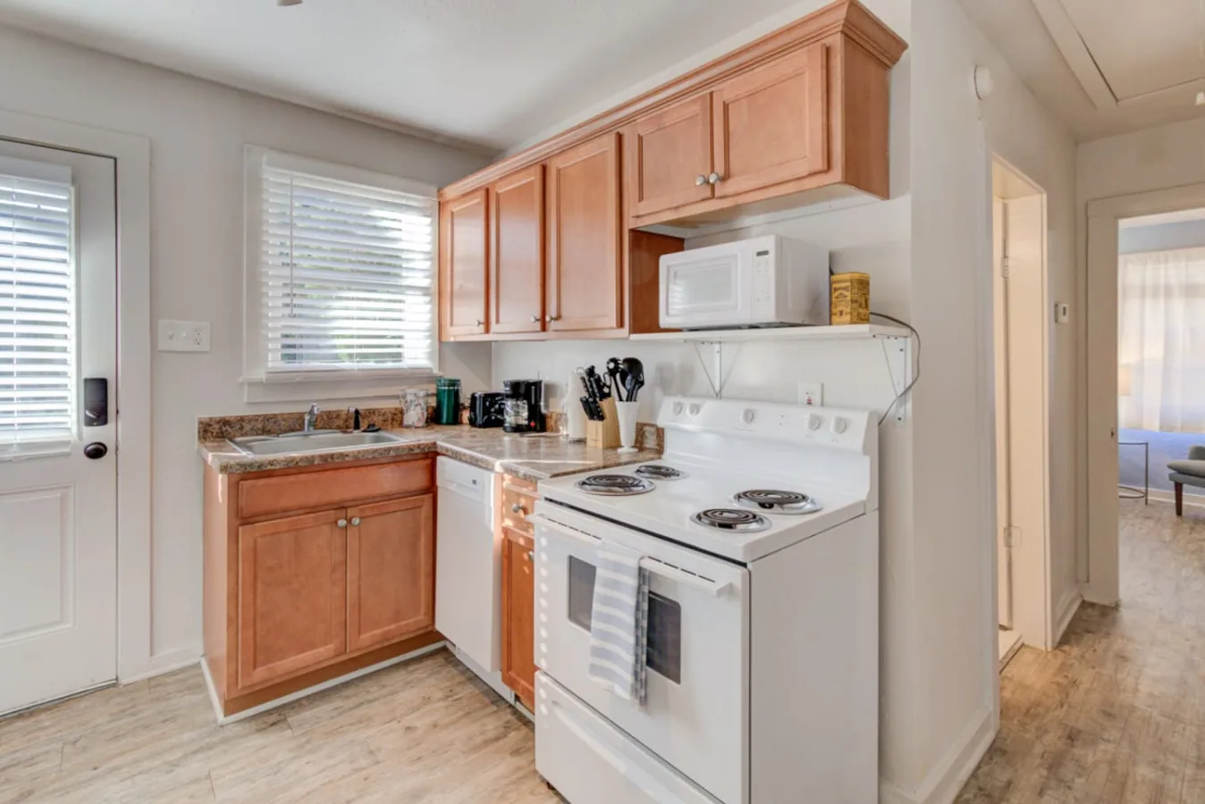 A compact kitchen with wooden cabinets and a white electric range.
